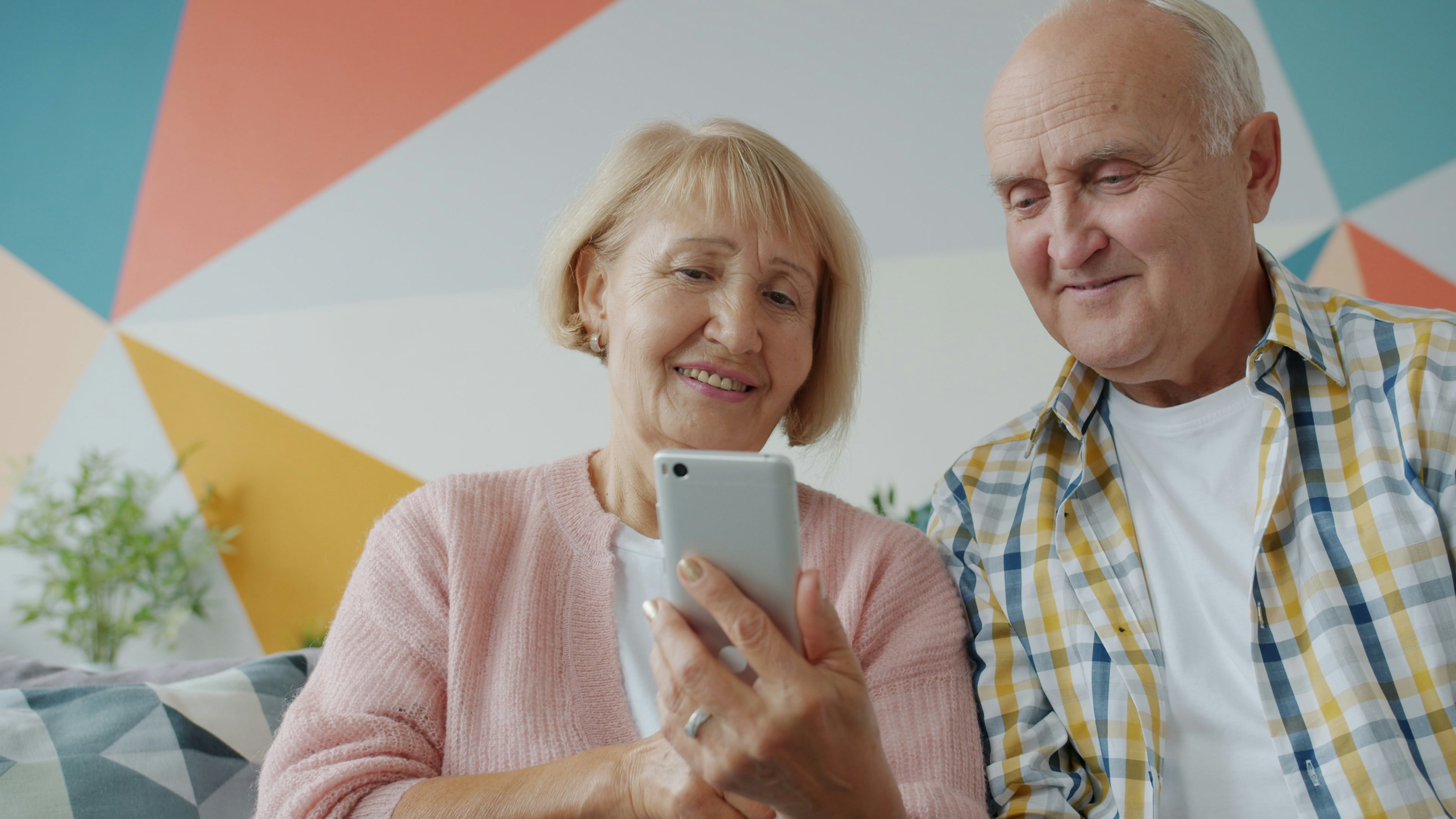 Photo of a couple smiling and using a smartphone